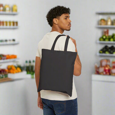 Man carrying a black tote bag on a white background