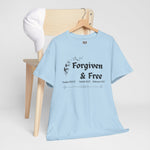 Light blue t-shirt with 'Forgiven & Free' text on a wooden hanger hung on chair against a white background